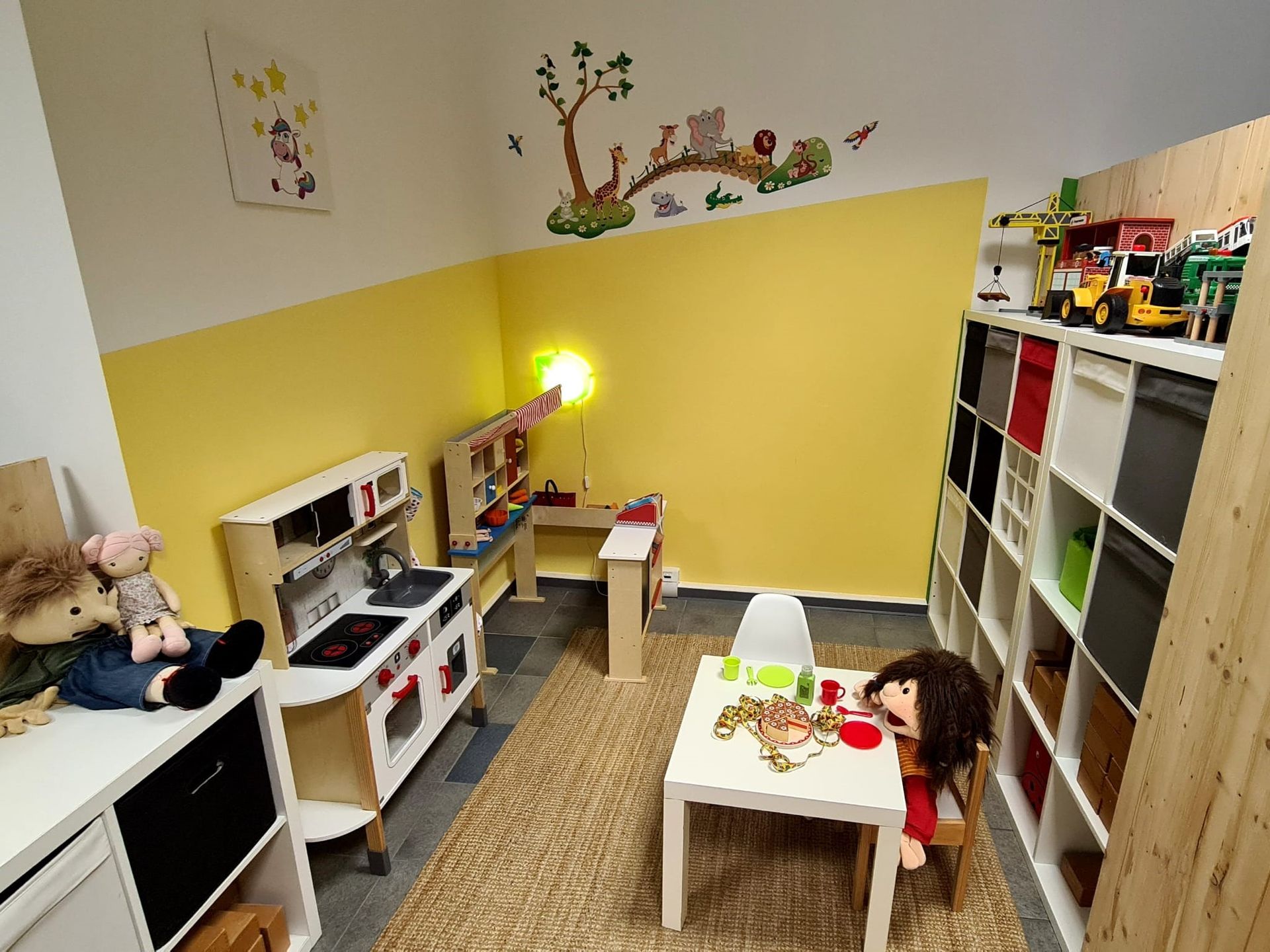 Ein Kinderspielzimmer mit Tisch, Stühlen, Spielzeug und einer Küche.