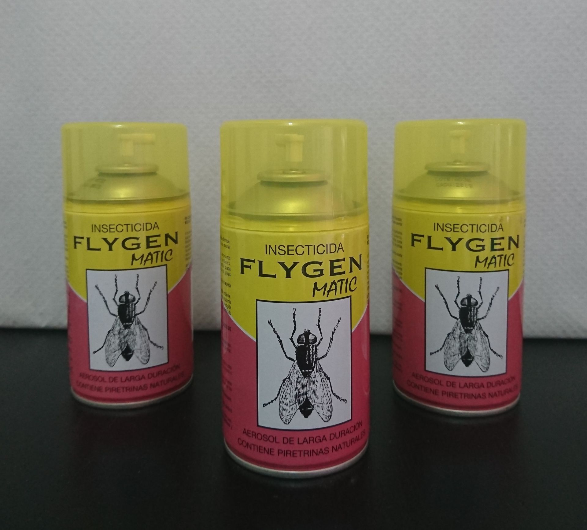 Tres botellas de Flygen Matic están sobre una mesa.