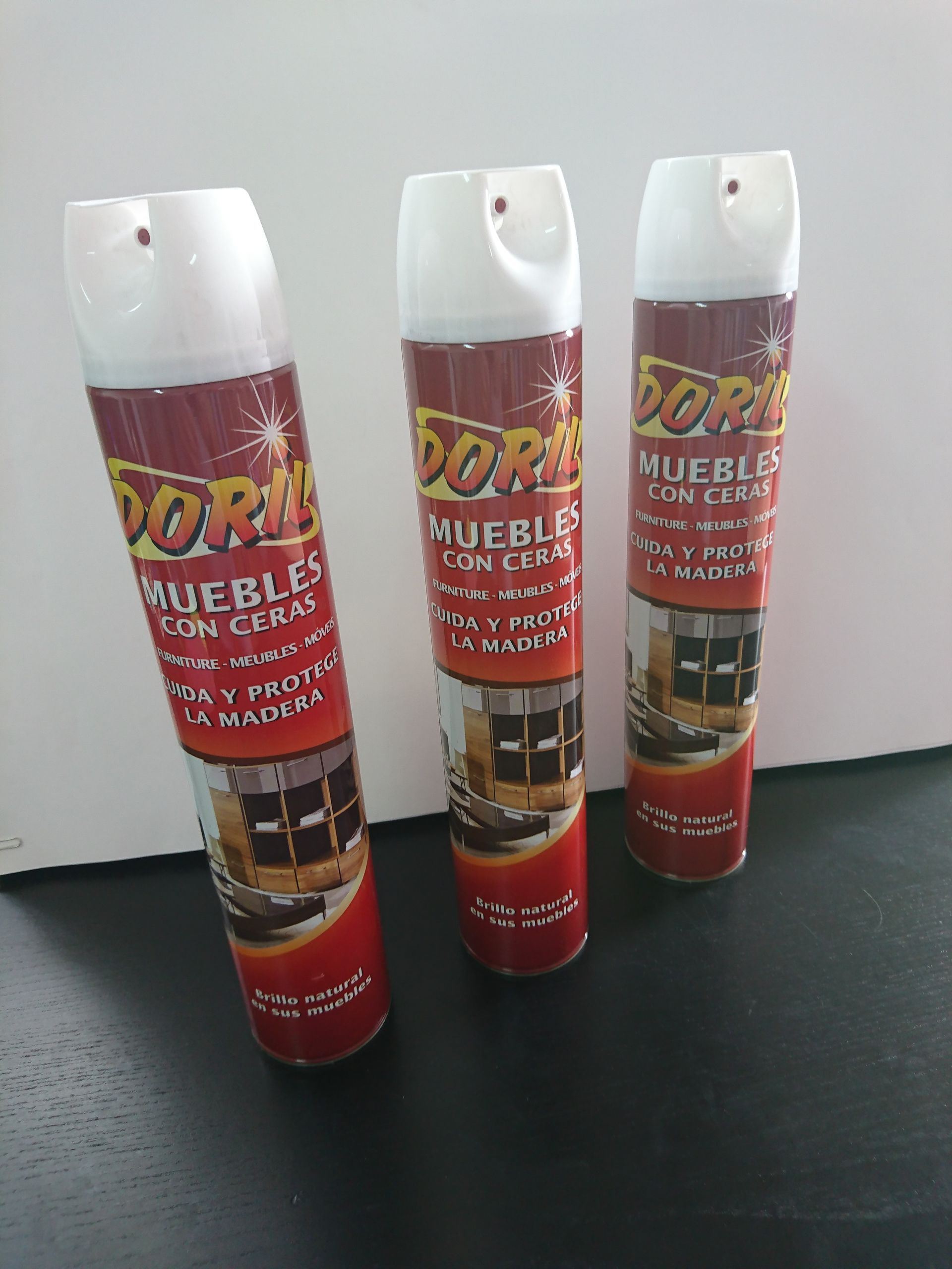 Hay tres latas de abrillantador de muebles Dora sobre una mesa.
