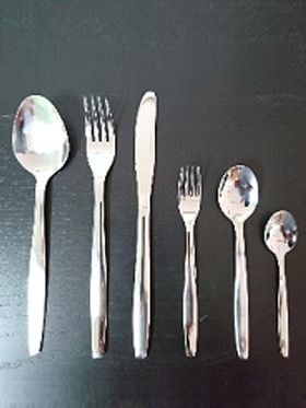 Una fila de cubiertos que incluyen cucharas, tenedores y cuchillos sobre una mesa negra.