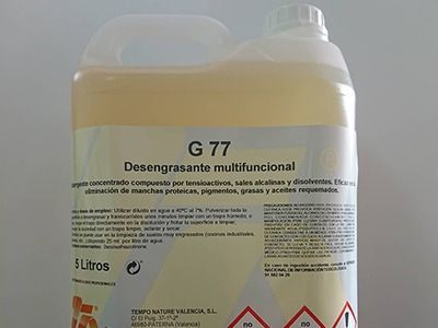 Una botella de g77 desengrasante multifuncional está sobre una superficie blanca.
