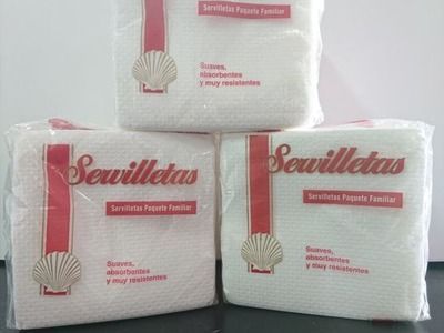 Tres bolsas de servilletas están apiladas una encima de otra sobre una mesa.