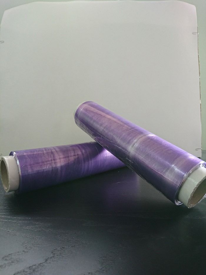 Hay dos rollos de film plástico morado sobre una mesa.