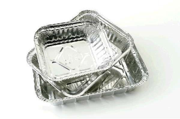 Tres bandejas de papel de aluminio están apiladas una encima de otra sobre una superficie blanca.