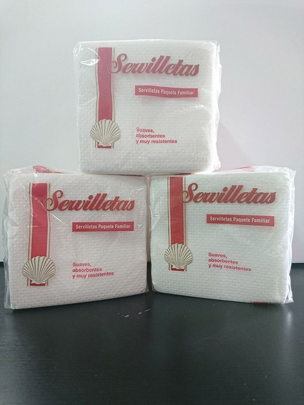 Tres bolsas de servilletas están apiladas una encima de otra sobre una mesa.