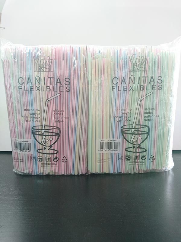 Dos bolsas de pajitas de plástico de colores están sobre una mesa.