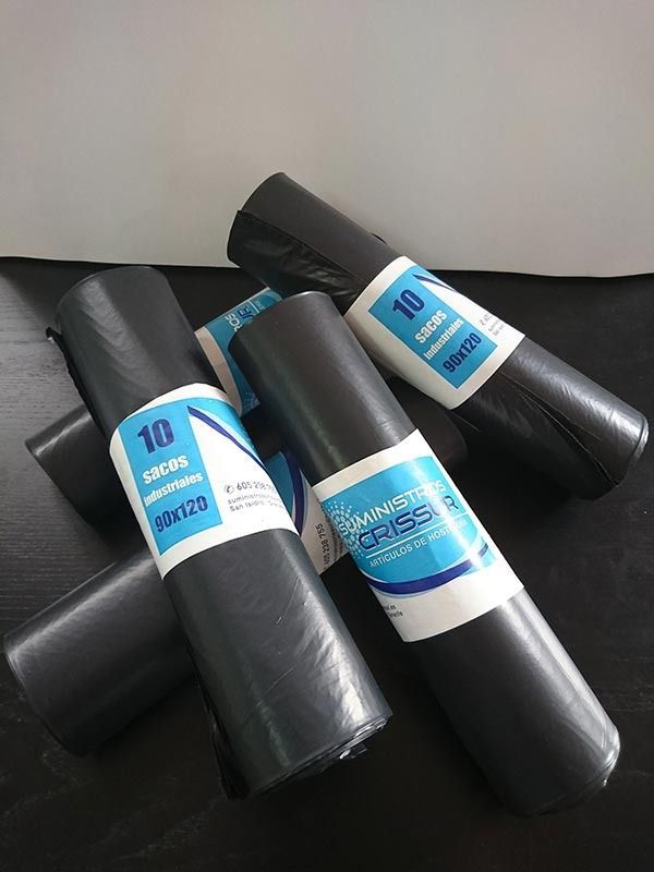 Tres bolsas de basura negras están apiladas una encima de otra sobre una mesa.