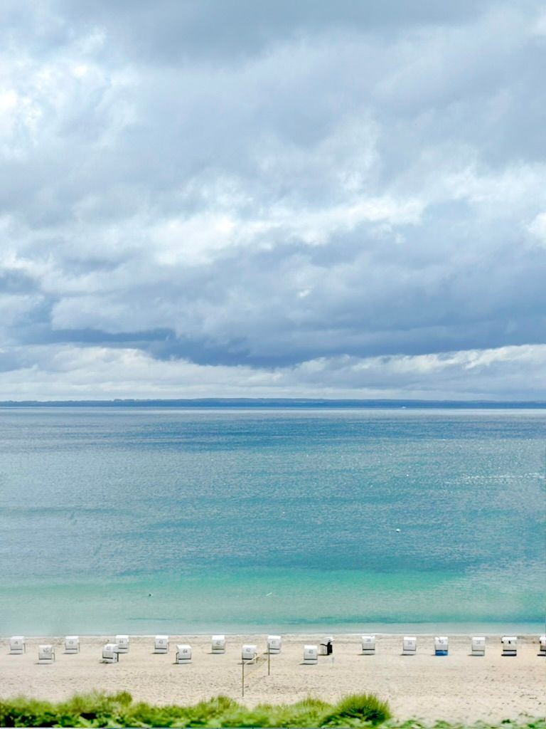 Strandkörbe am türkisfarbenen Ostseestrand unter Wolkenhimmel in Sierksdorf