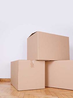 Tres cajas de cartón están apiladas una encima de otra sobre un piso de madera.