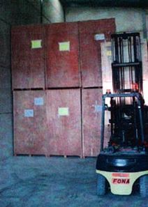 Una carretilla elevadora está estacionada frente a un almacén lleno de cajas de madera.