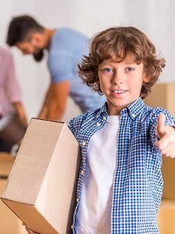 Un niño sostiene una caja de cartón y apunta a la cámara.