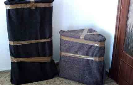 Dos bolsas envueltas en film plástico están una al lado de la otra en una habitación.