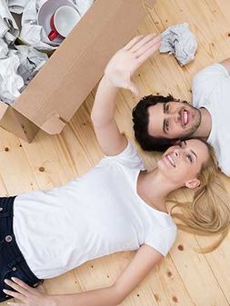 Un hombre y una mujer están acostados en el suelo junto a una caja de cartón.