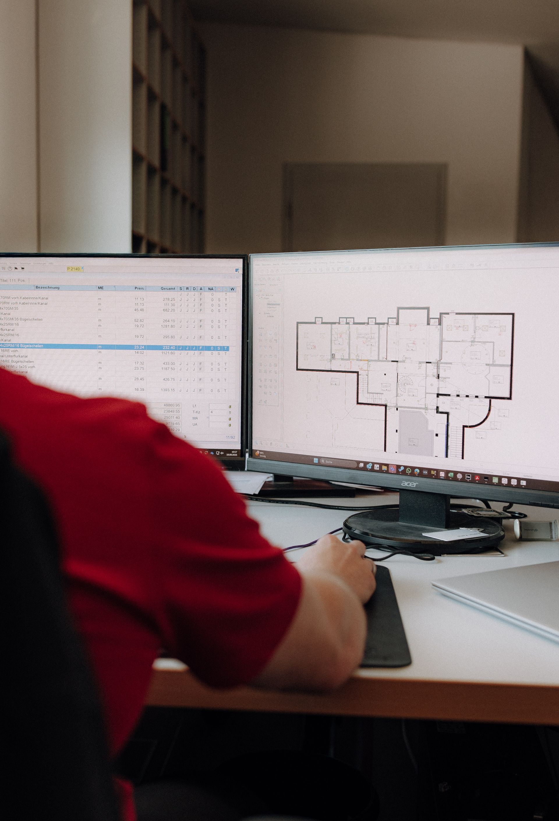 Arbeitsplatz mit Bauplänen und technischer Dokumentation am Bildschirm
