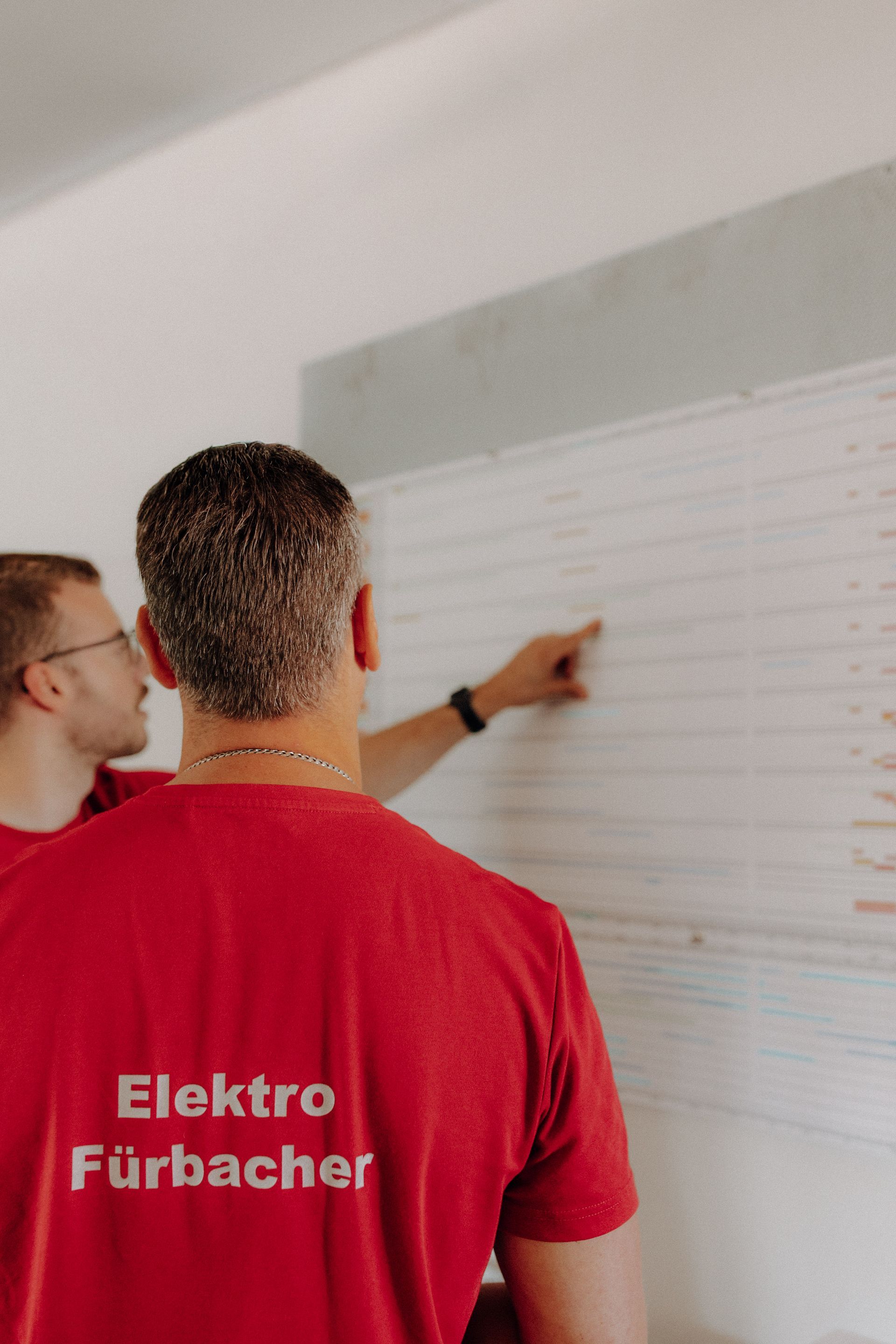 Elektrofachkräfte besprechen technische Details an einer Planungstafel