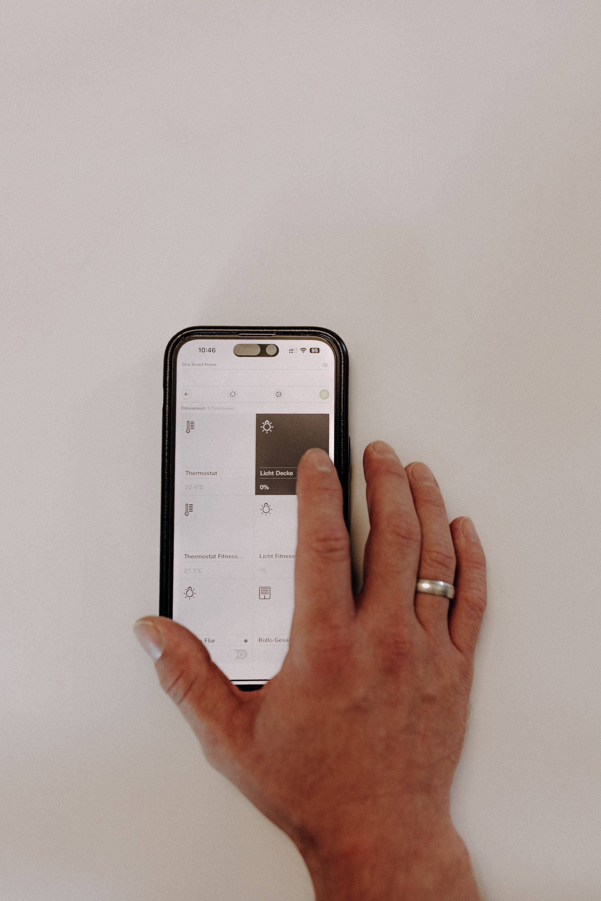 Hand bedient eine Smart-Home-App auf einem Smartphone