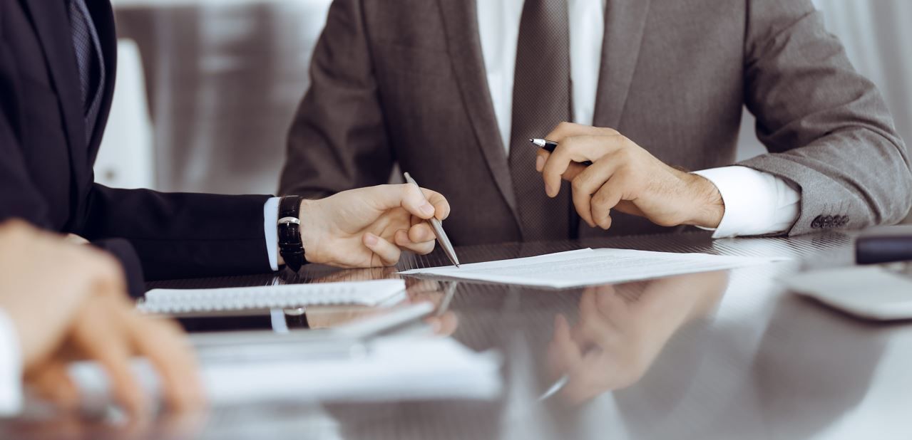 Un profesional del derecho habla con un cliente en un escritorio, con un mazo de madera en primer plano.