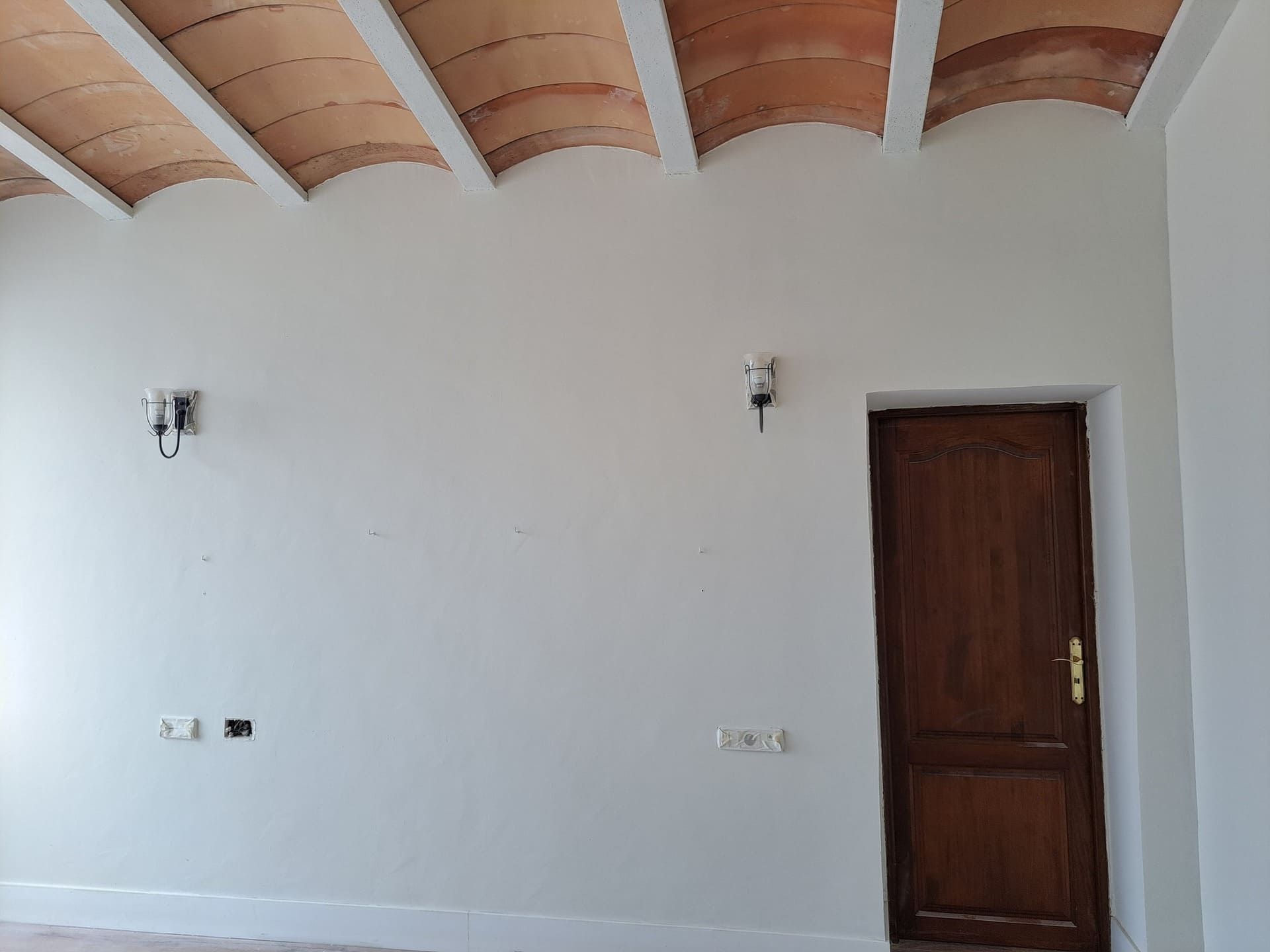 Una habitación vacía con una puerta de madera y un techo de baldosas.