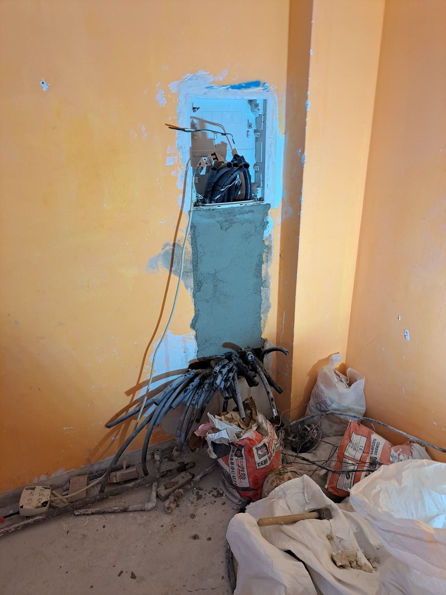 Una habitación con un agujero en la pared y un montón de cables saliendo de él.