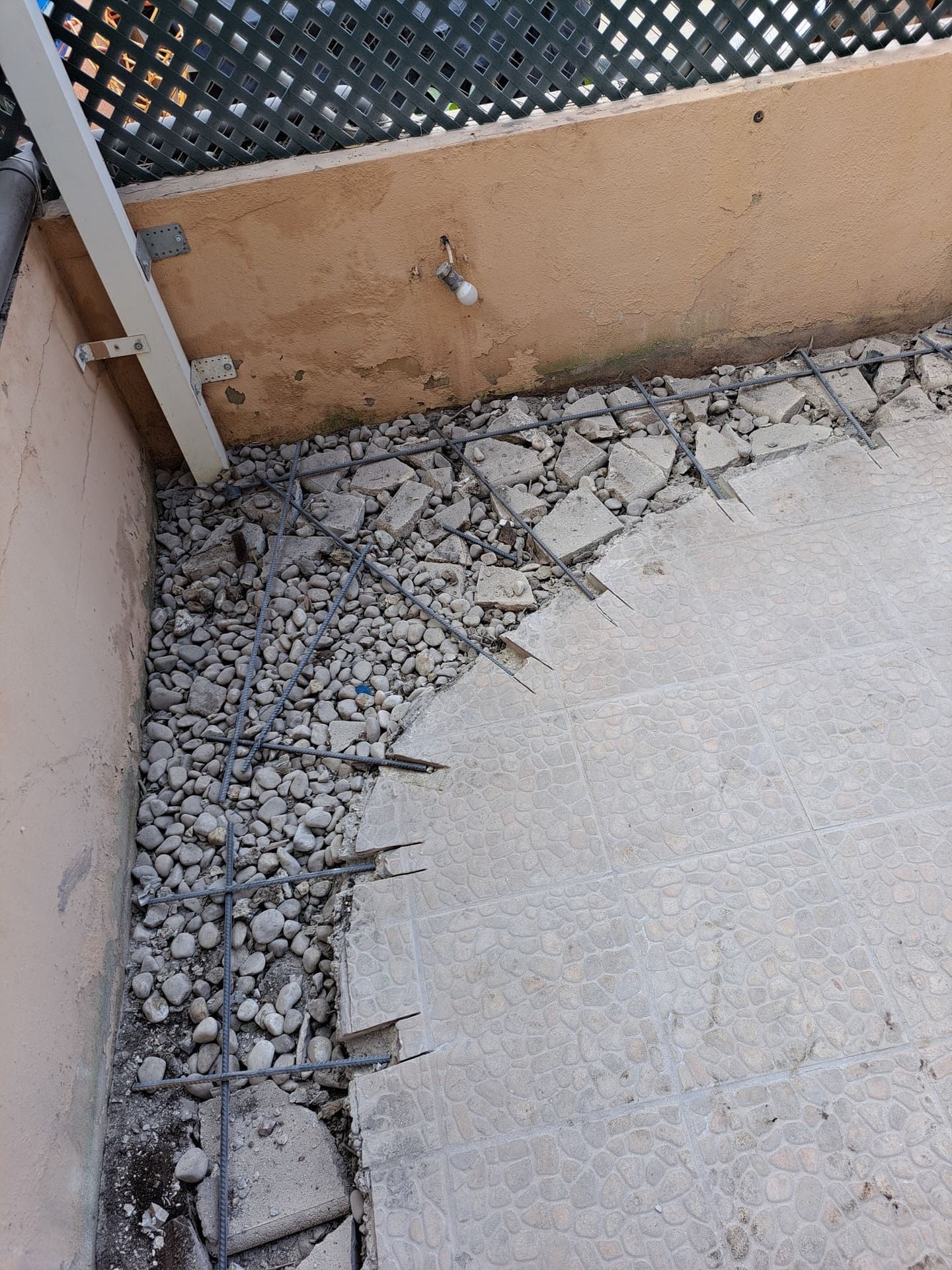 Un suelo de hormigón con rocas y una valla al fondo.