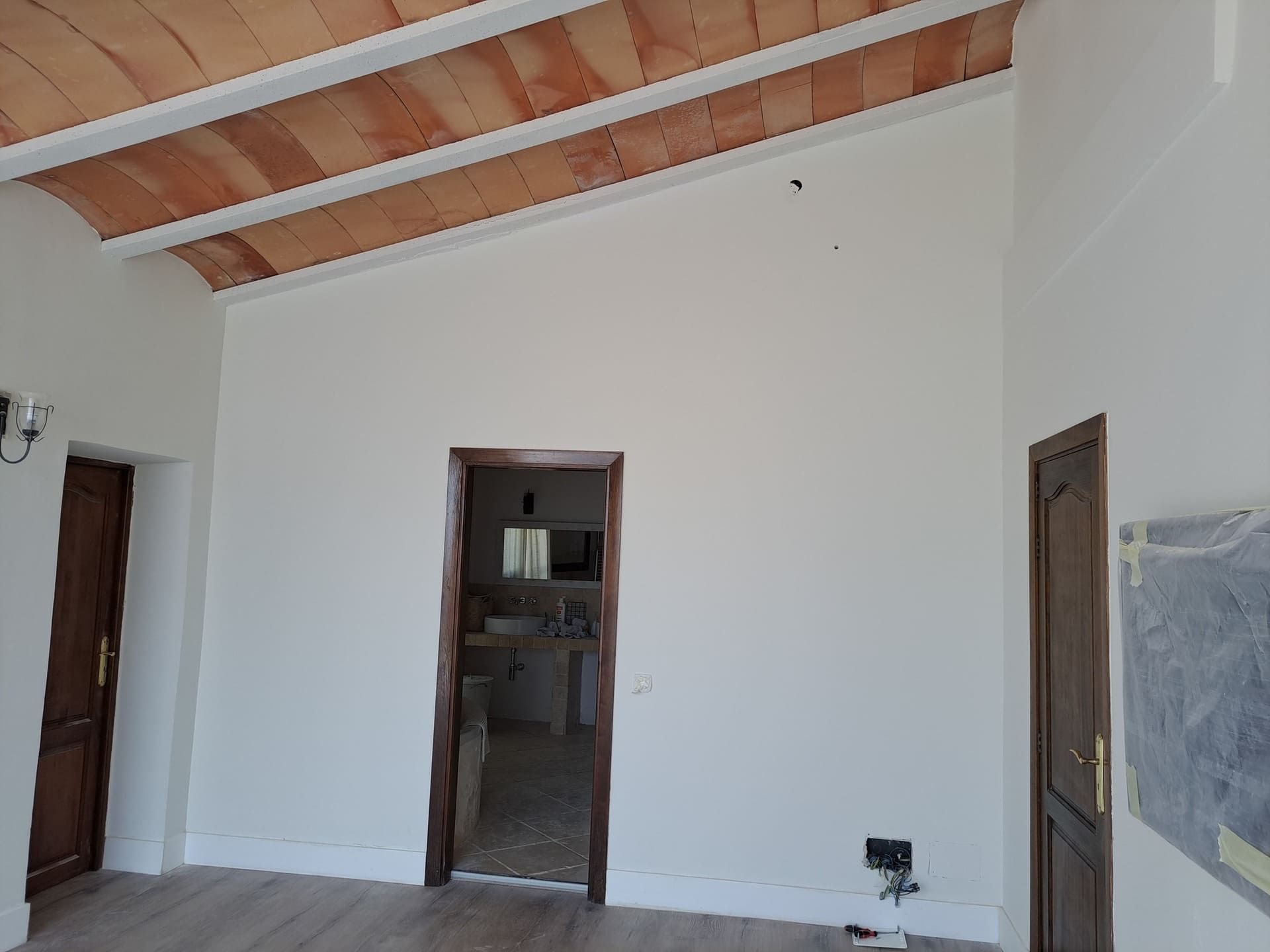 Una habitación vacía con techo de madera y paredes blancas.