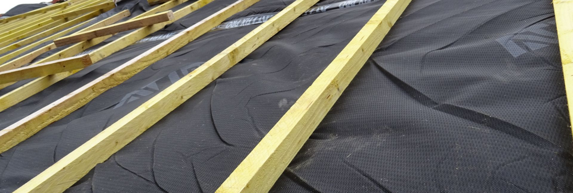 Chevrons de toit en bois avec sous-couche noire.