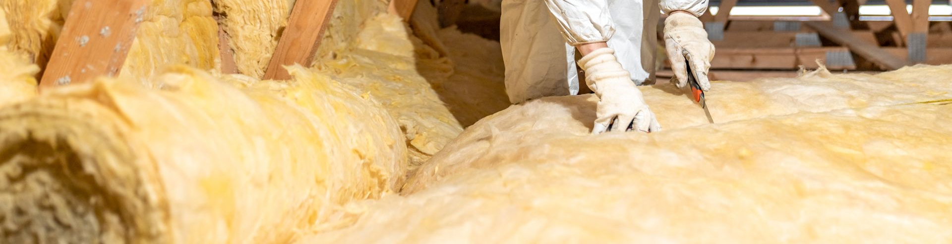 Personne portant des vêtements de protection travaillant avec de l'isolant dans un grenier.