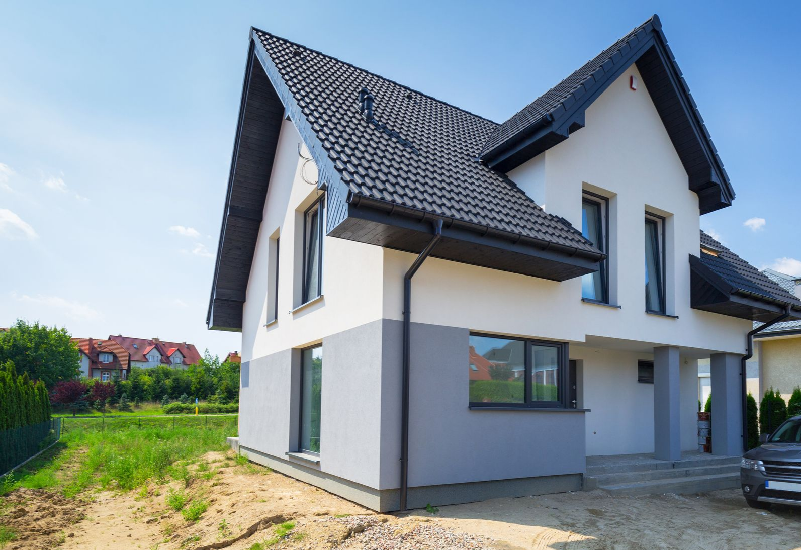 Une maison moderne à deux étages, avec une façade blanche et grise.