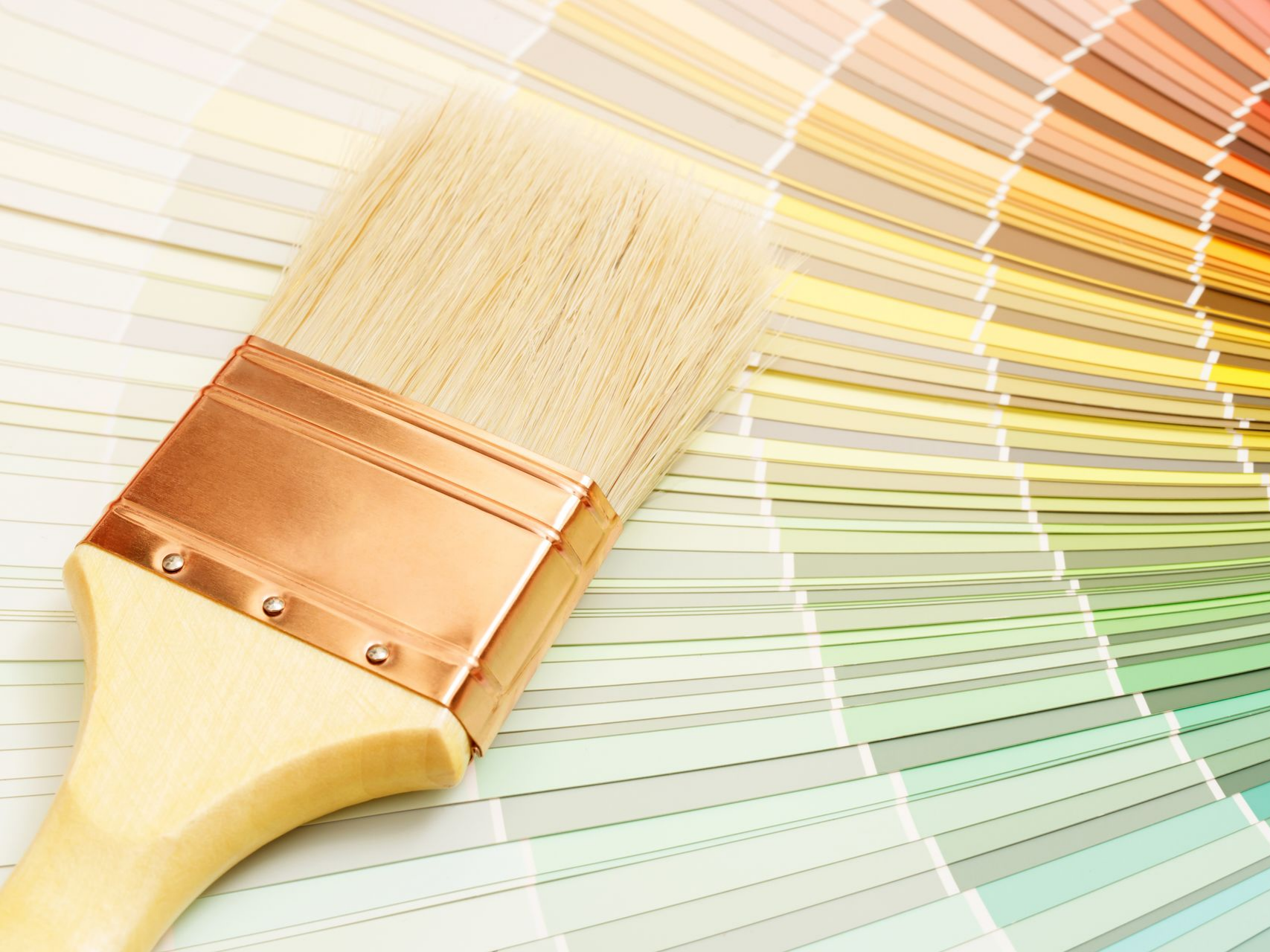 Un pinceau en bois posé sur un éventail coloré d'échantillons de peinture.