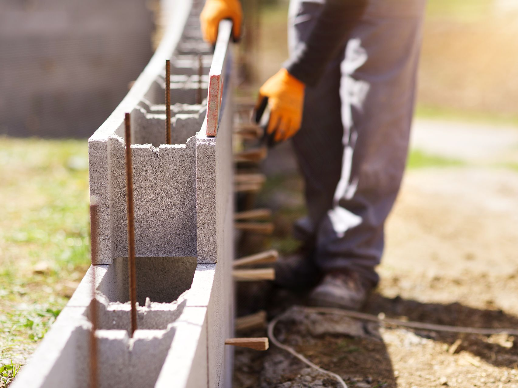 Un ouvrier portant des gants utilise un niveau pour aligner des blocs de béton.