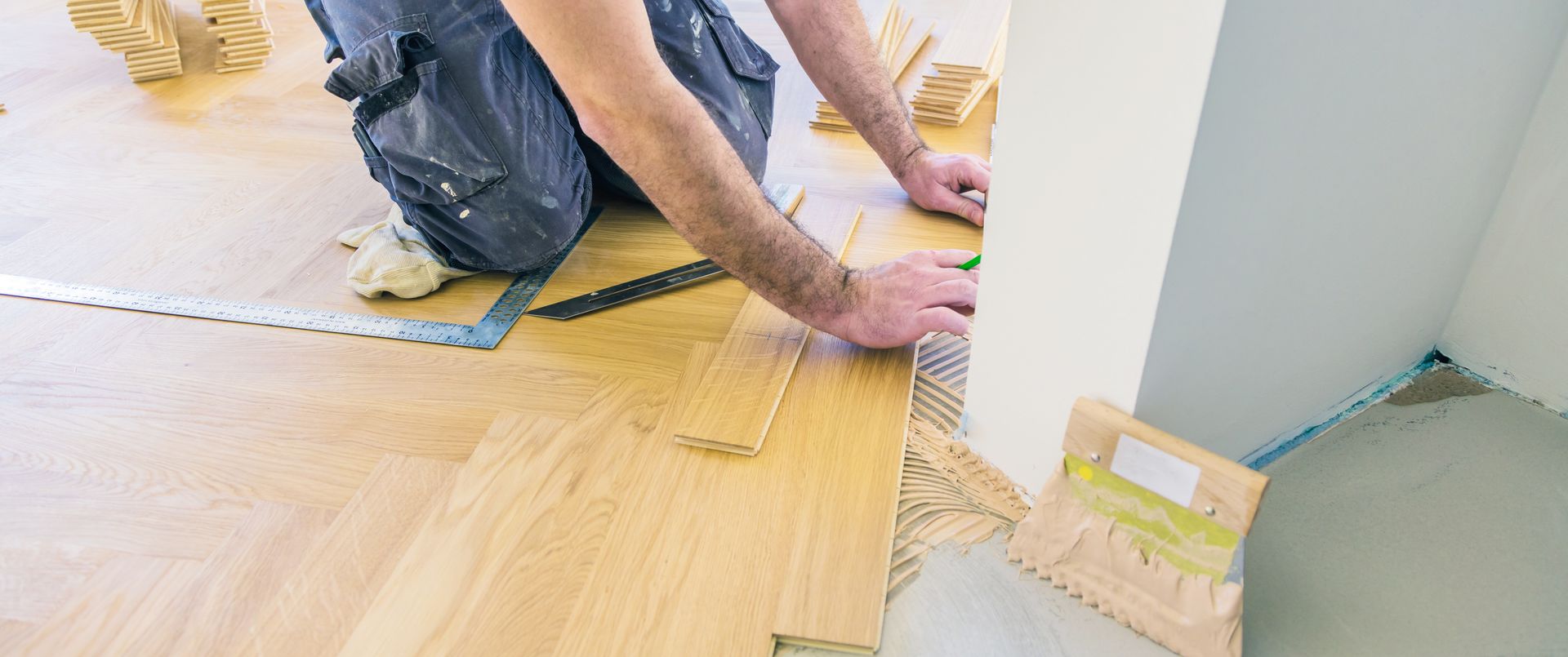 Un homme installe un parquet dans une pièce.