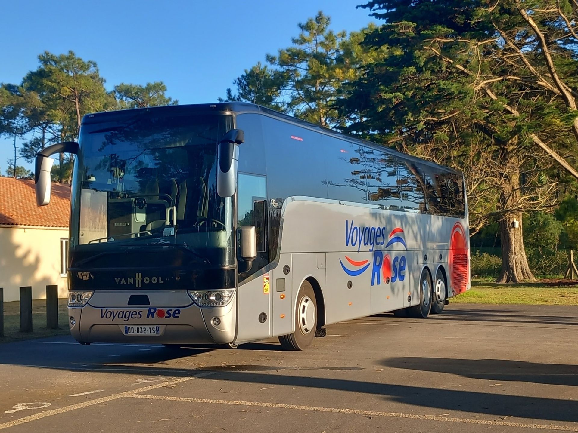 Un bus gris Voyages Rose est garé dehors.