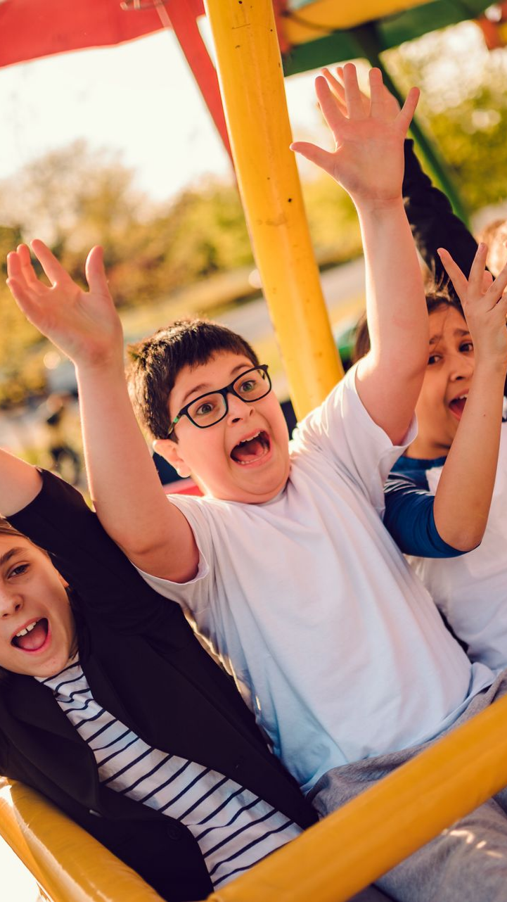 Des enfants sur un manège tournant, les bras levés d'excitation.