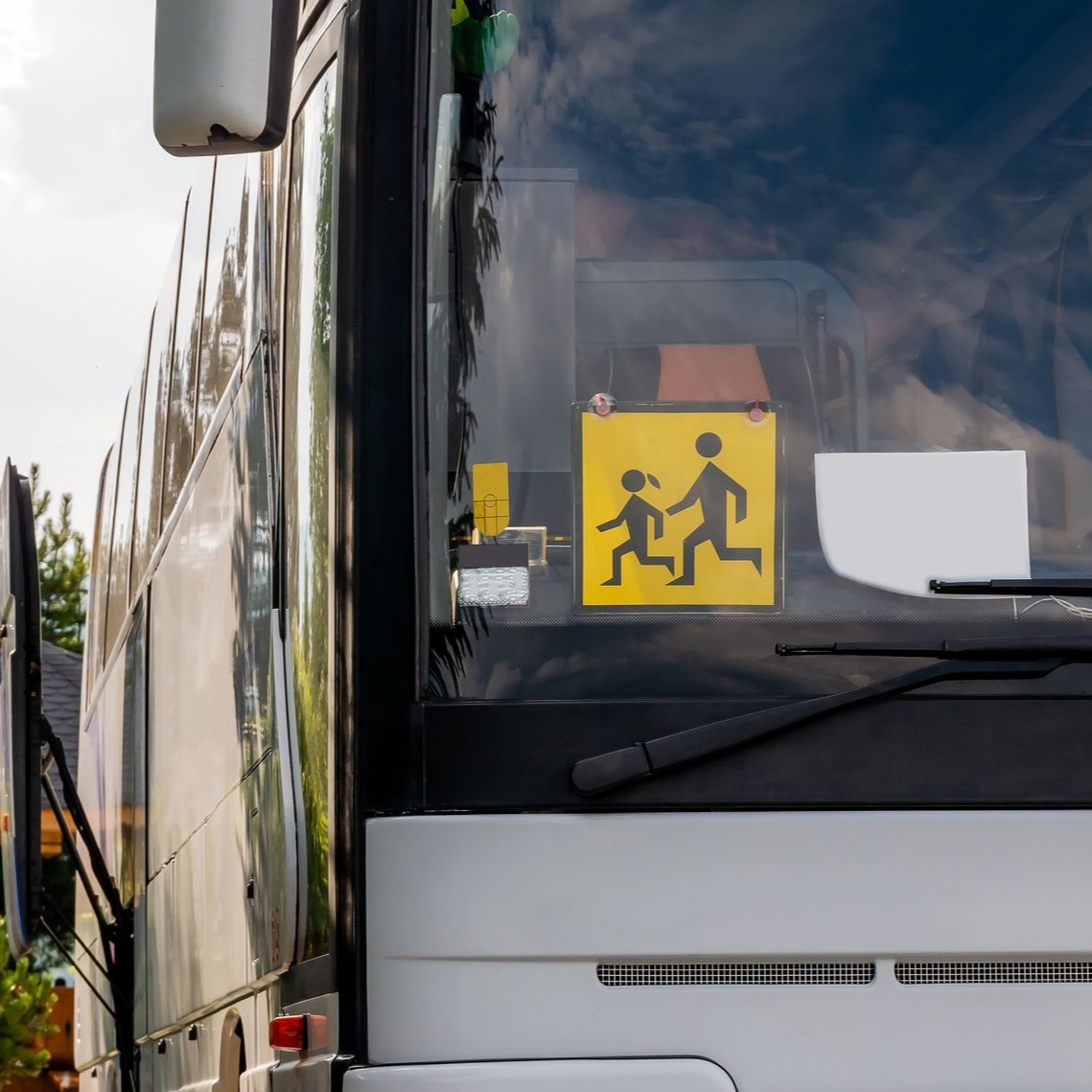 Autobus scolaire avec un panneau attention enfants de couleur jaune derrière le pare-brise.