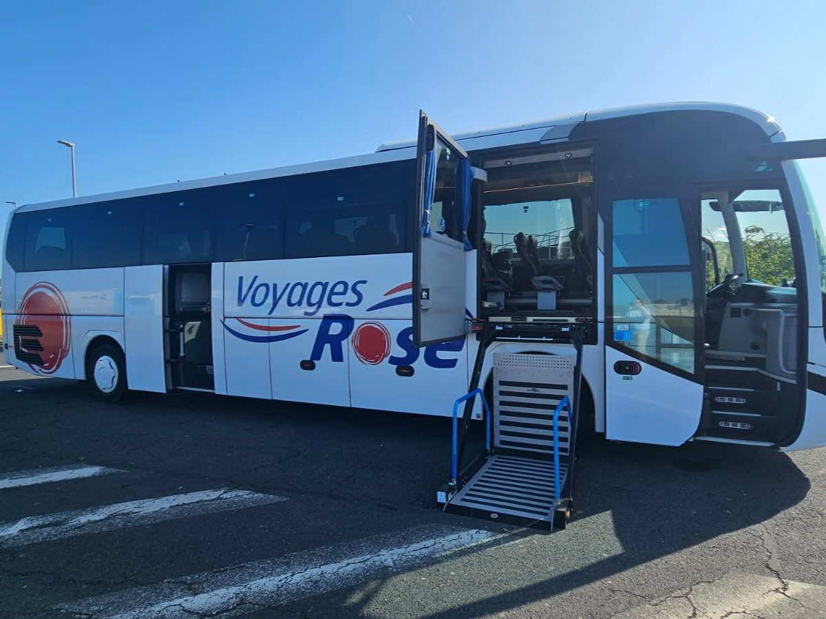 Autobus blanc des Voyages Rose avec la porte ouverte et la rampe d'accès PMR déployée.