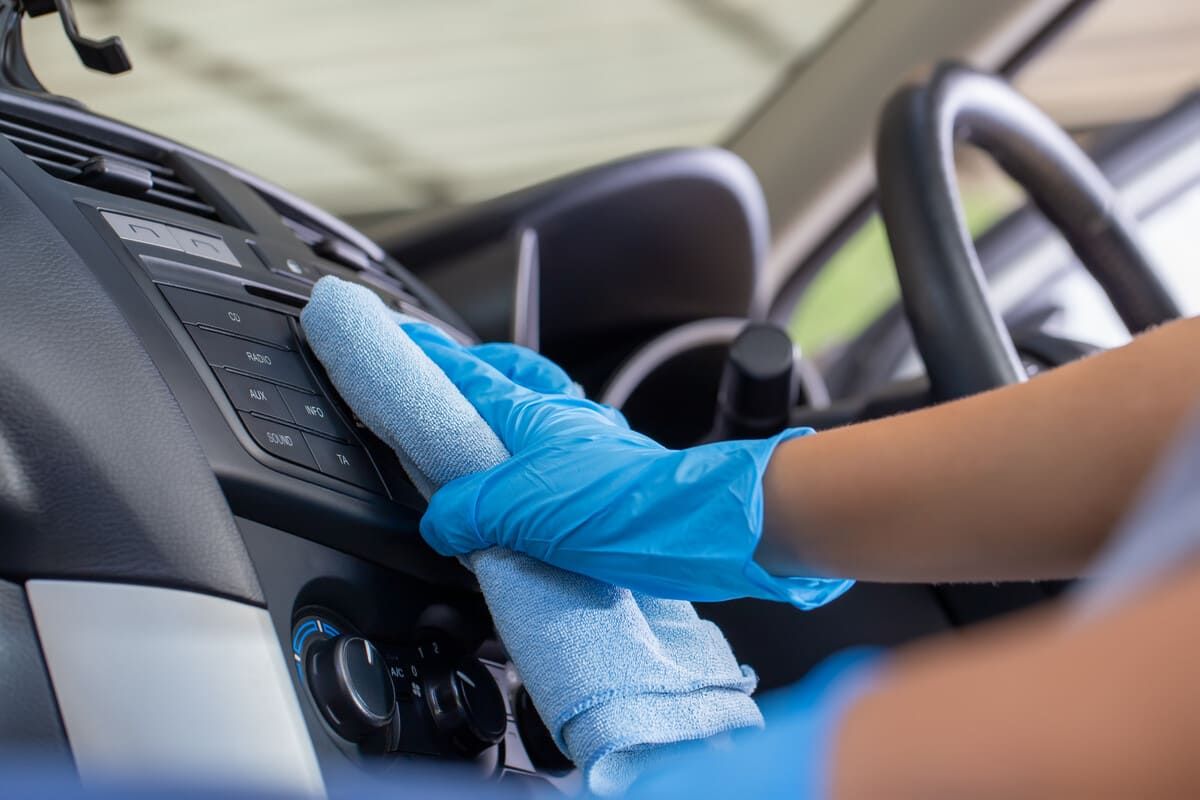 Una persona que lleva guantes azules está limpiando el salpicadero de un coche.