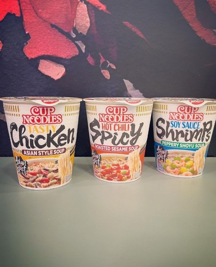 Hay tres tazas de fideos instantáneos sobre una mesa.