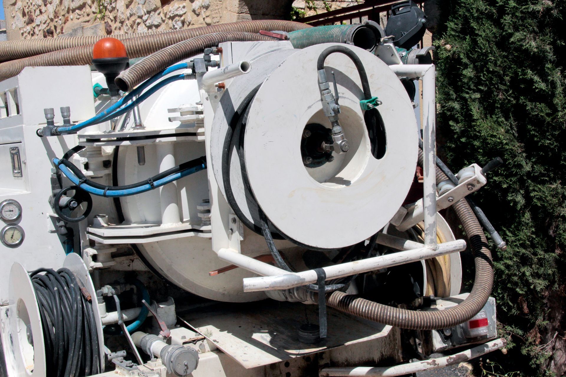 Machine industrielle blanche avec tuyaux et câbles sur un chantier extérieur.