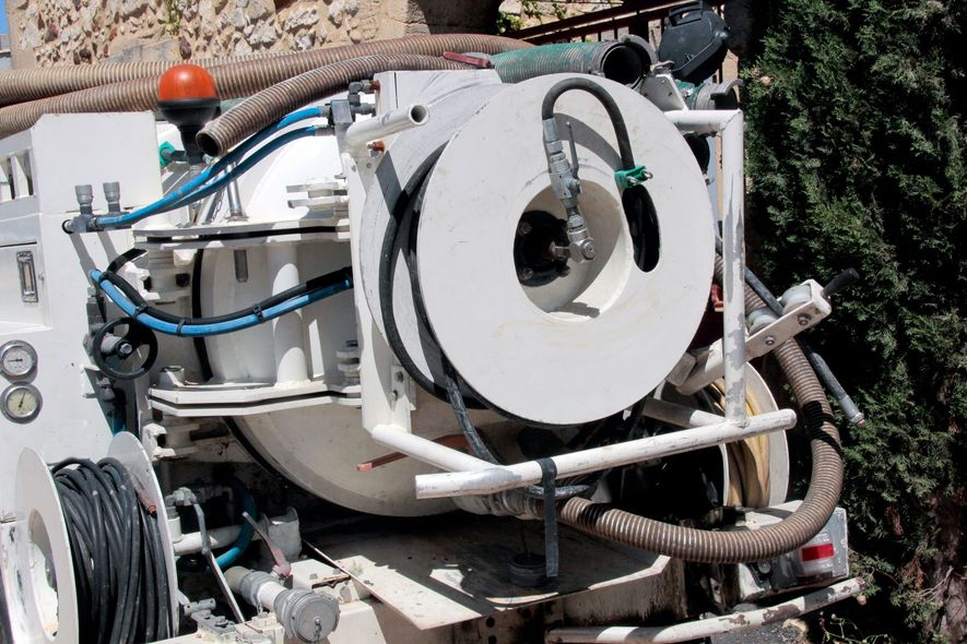 Machine industrielle blanche avec tuyaux et câbles sur un chantier extérieur