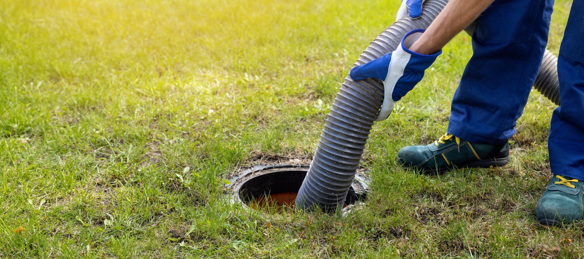 Un ouvrier utilise un tuyau ondulé pour nettoyer un trou dans une pelouse.
