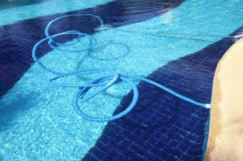 Una manguera azul está tendida en el suelo de una piscina.