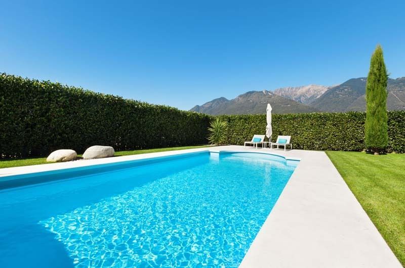 Hay una gran piscina en el patio trasero con montañas al fondo.