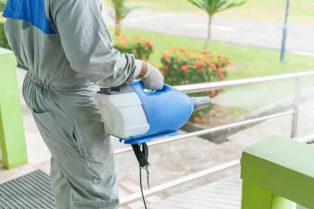 Un hombre está desinfectando un edificio con un pulverizador.
