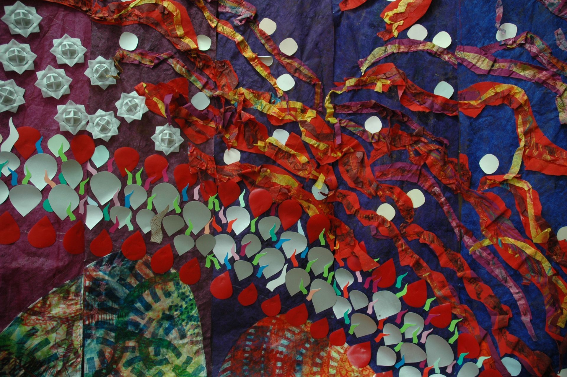 Primer plano de tiras geométricas multicolores superpuestas y piezas de cartón estampadas dispuestas en una composición similar a una cuadrícula.