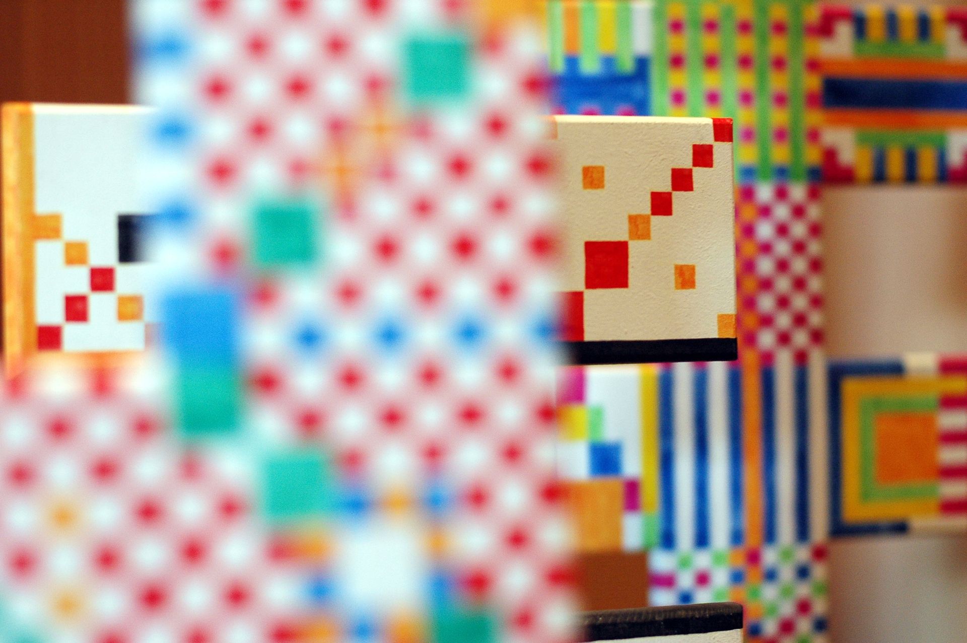 Un marco colorido con un patrón de cuadrícula en primer plano rodea una obra de arte abstracta geométrica más pequeña con patrones variados.