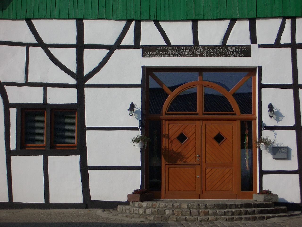 Dachgeschoss-Lounge mit grünem Sofa, farbenfrohen Hockern und Holzbalken. Dachfenster sorgen für natürliches Licht.