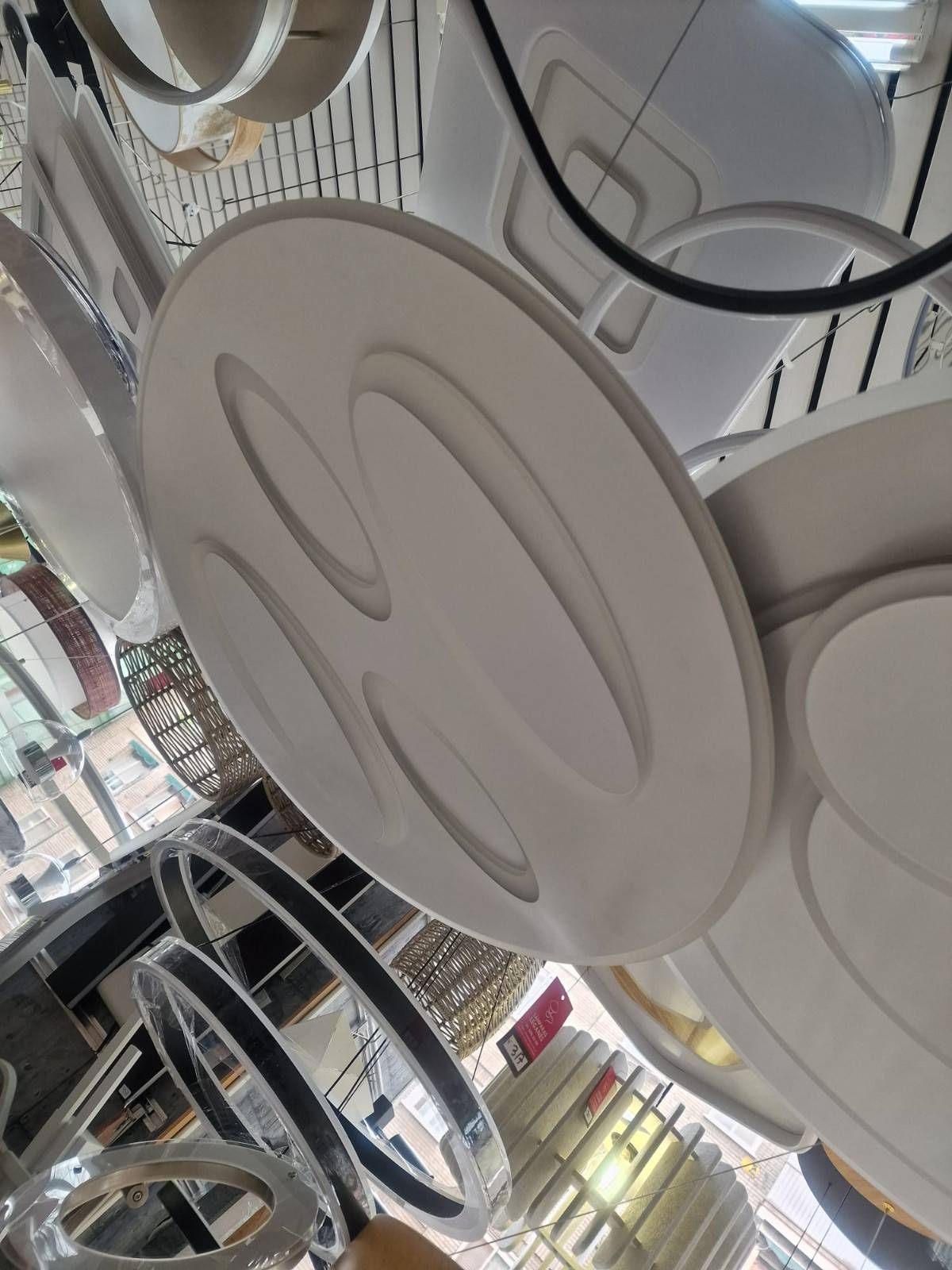 Una muestra de modernas lámparas de techo LED circulares blancas que cuelgan del techo de una tienda