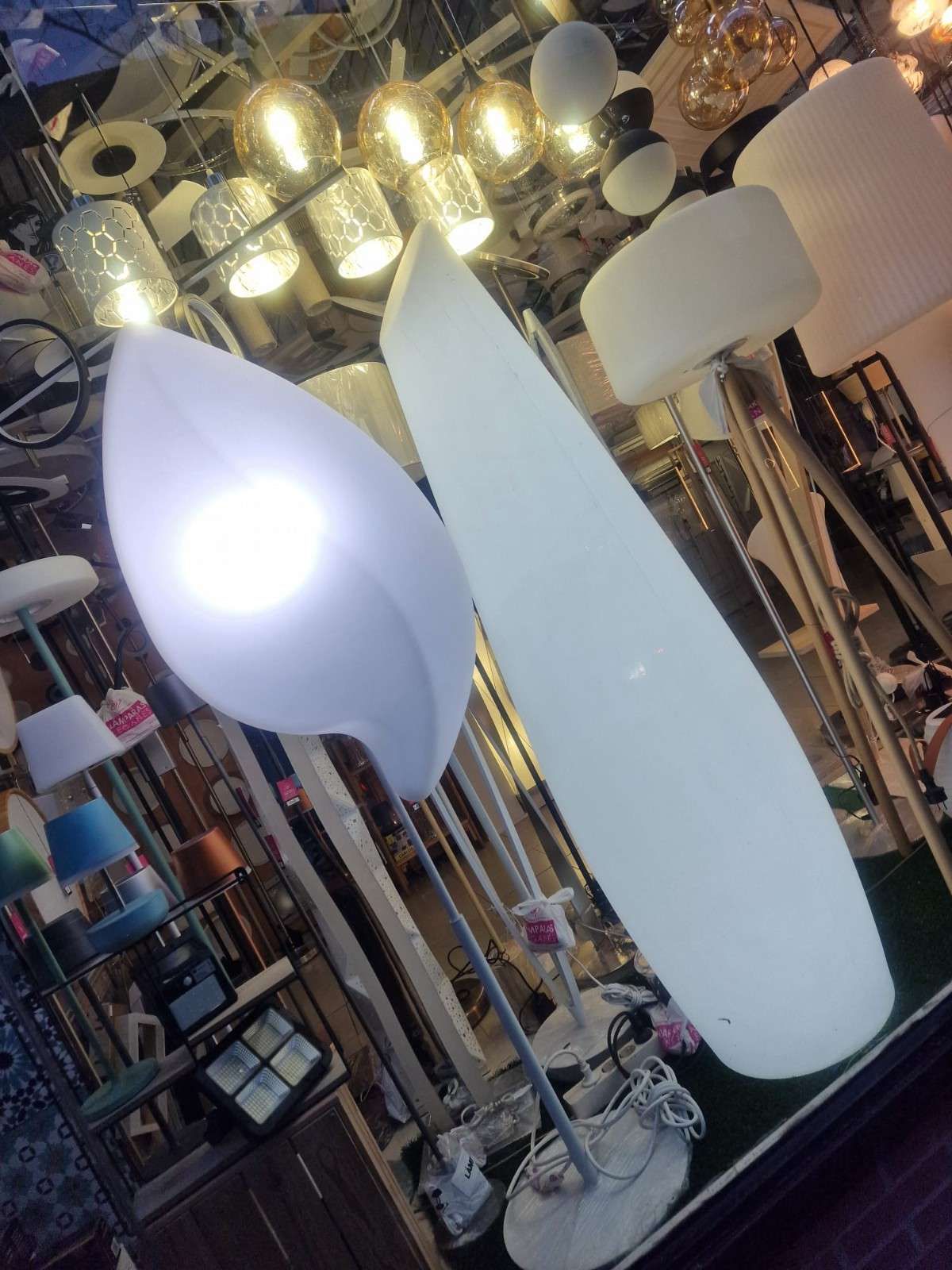 En una tienda se puede ver una exposición de modernas lámparas de pie blancas iluminadas