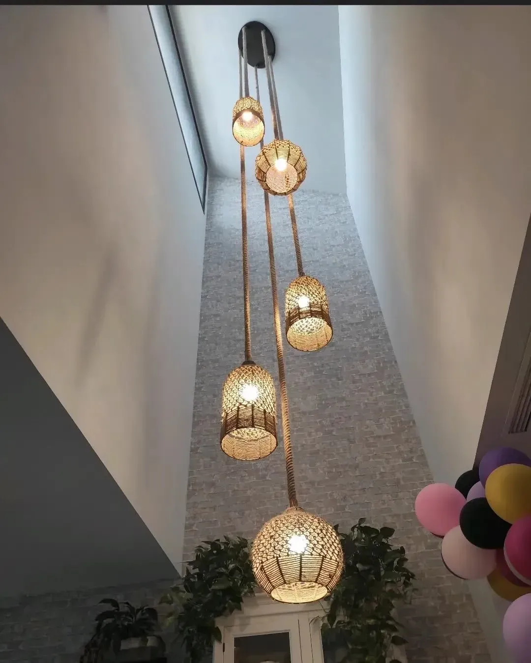 Una lámpara de araña escalonada con cinco luces colgantes luminosas de color dorado y textura de malla