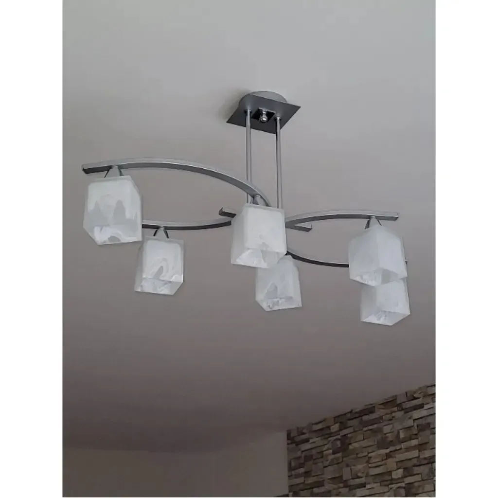 Una moderna lámpara de araña de cinco luces con pantallas de vidrio esmerilado y una estructura metálica